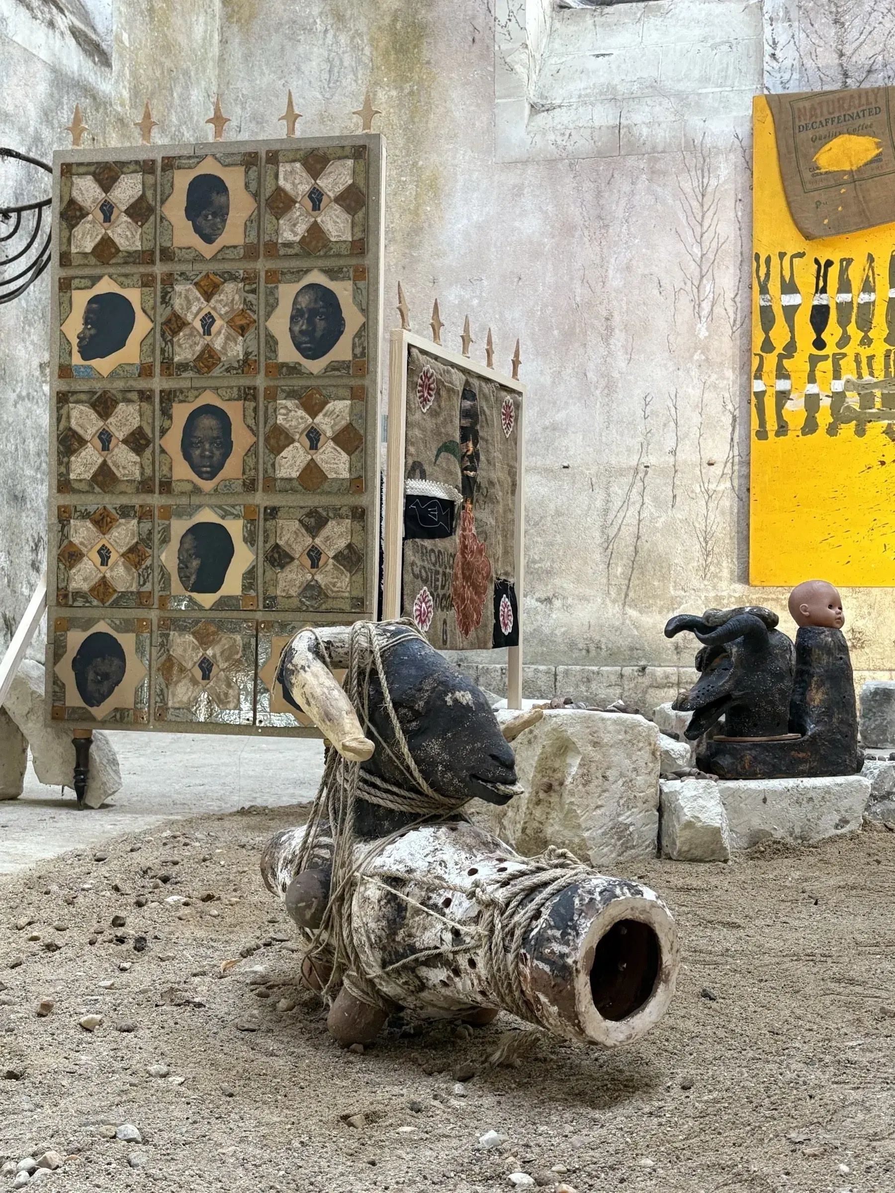 Sculptural figure in the foreground of the central installation, surrounded by panels and stone blocks.