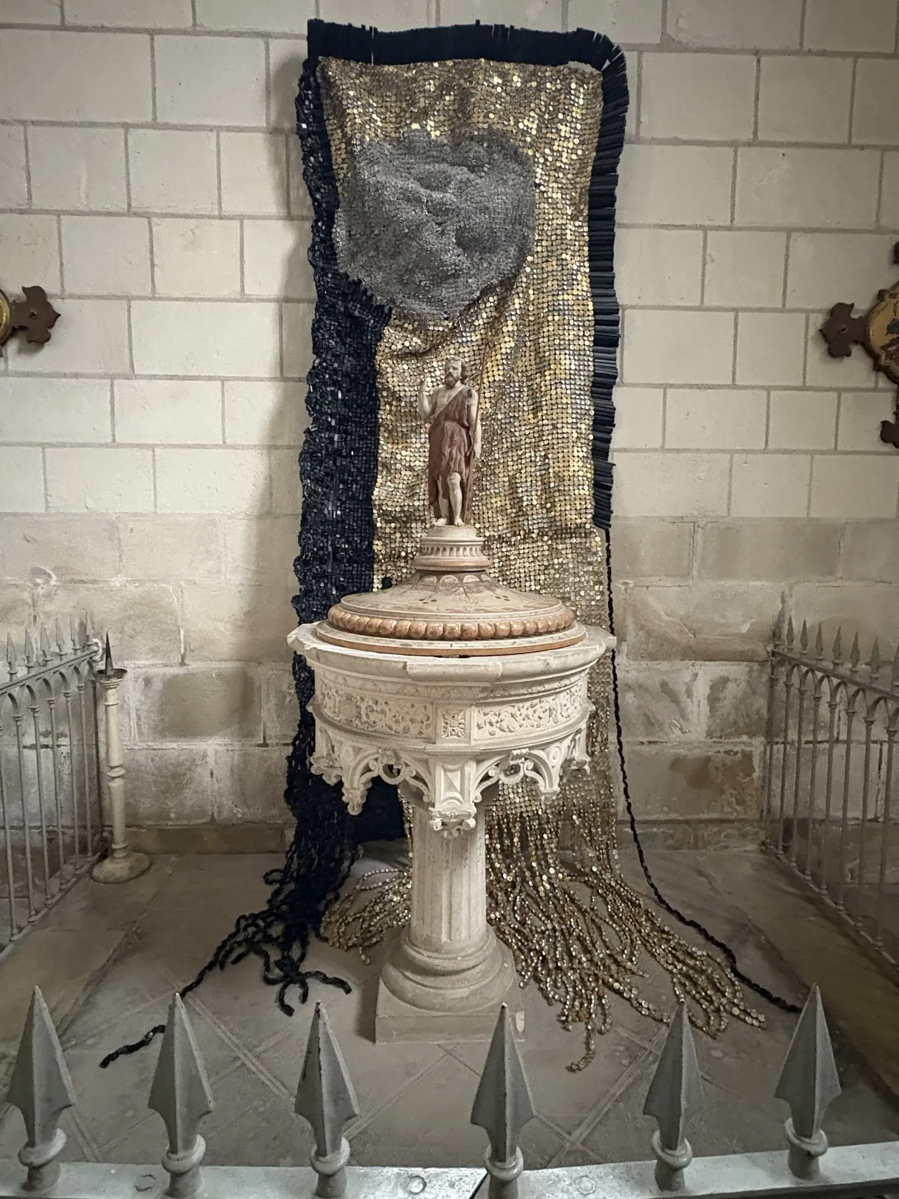 Moffat Takadiwa’s recycled-material installation framing the baptismal font in the church of Saint-Épain.