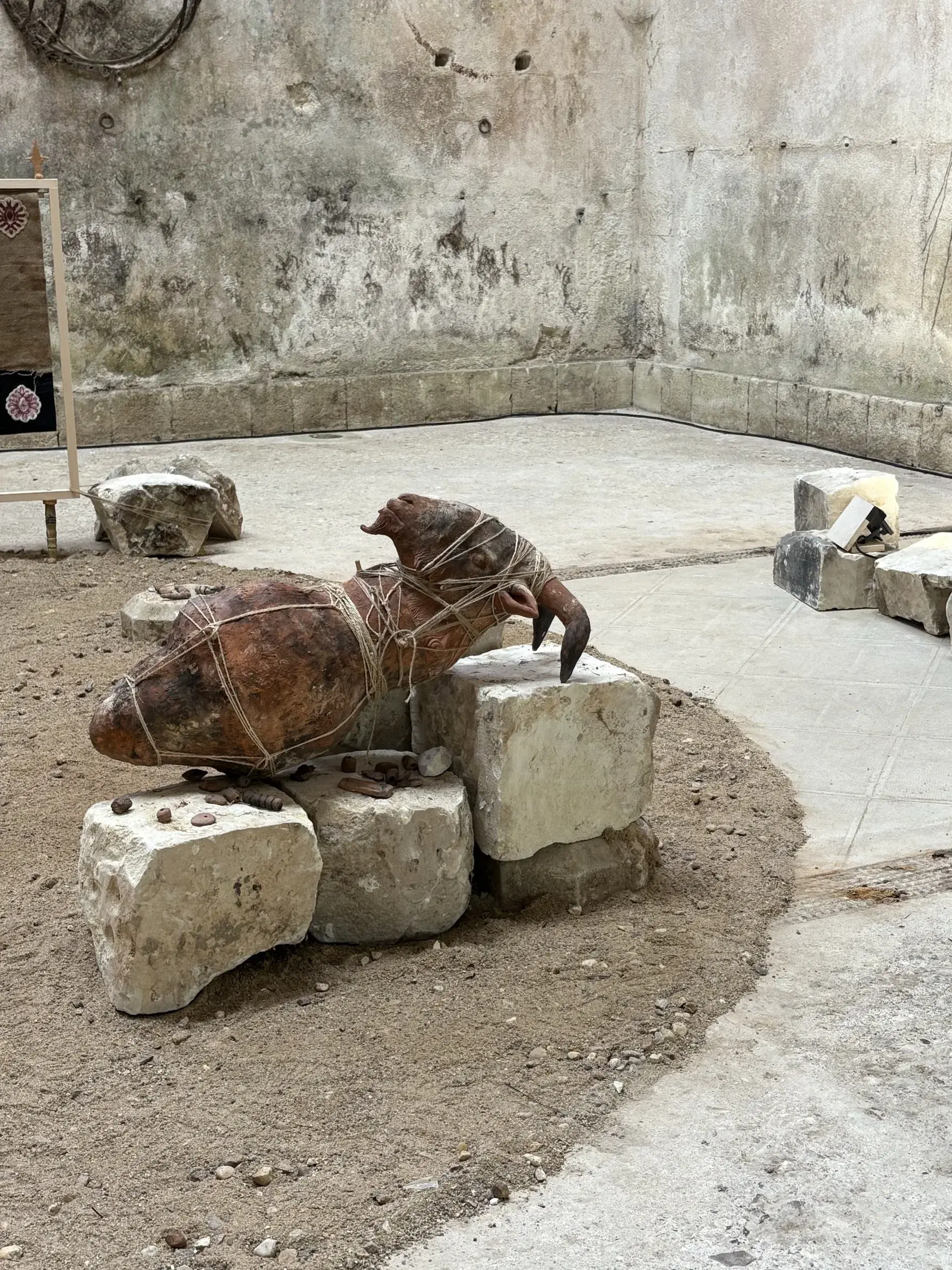 Bound horse-like sculpture resting on blocks of stone within the exhibition.