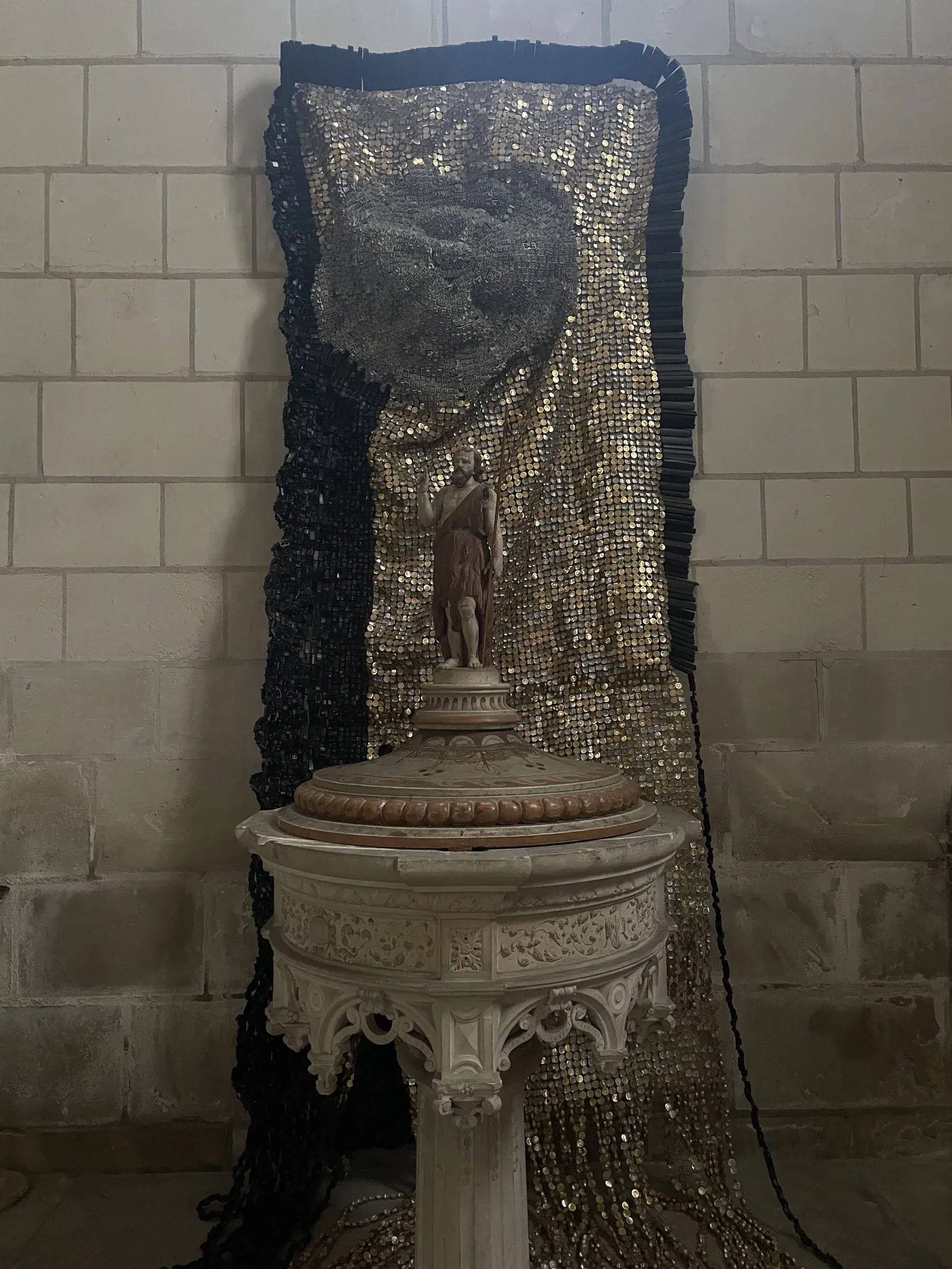 Moffat Takadiwa’s shimmering recycled-material installation behind the baptismal font.