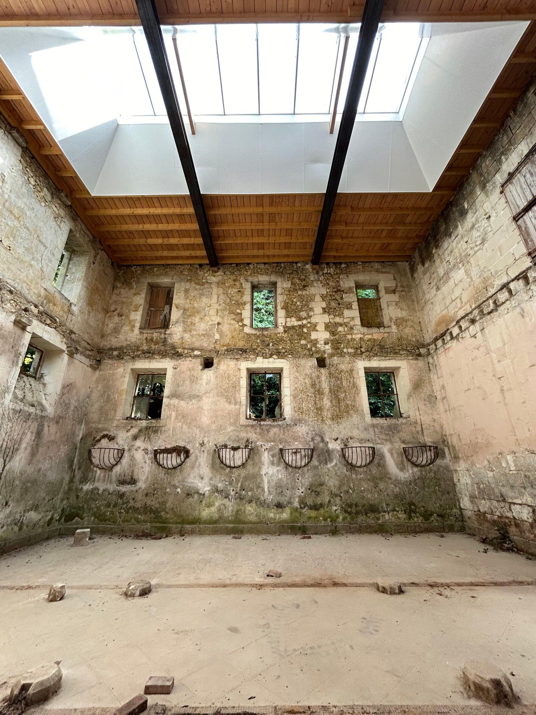 A tall architectural space at Château de Montgoger with contemporary works installed above the stone walls.